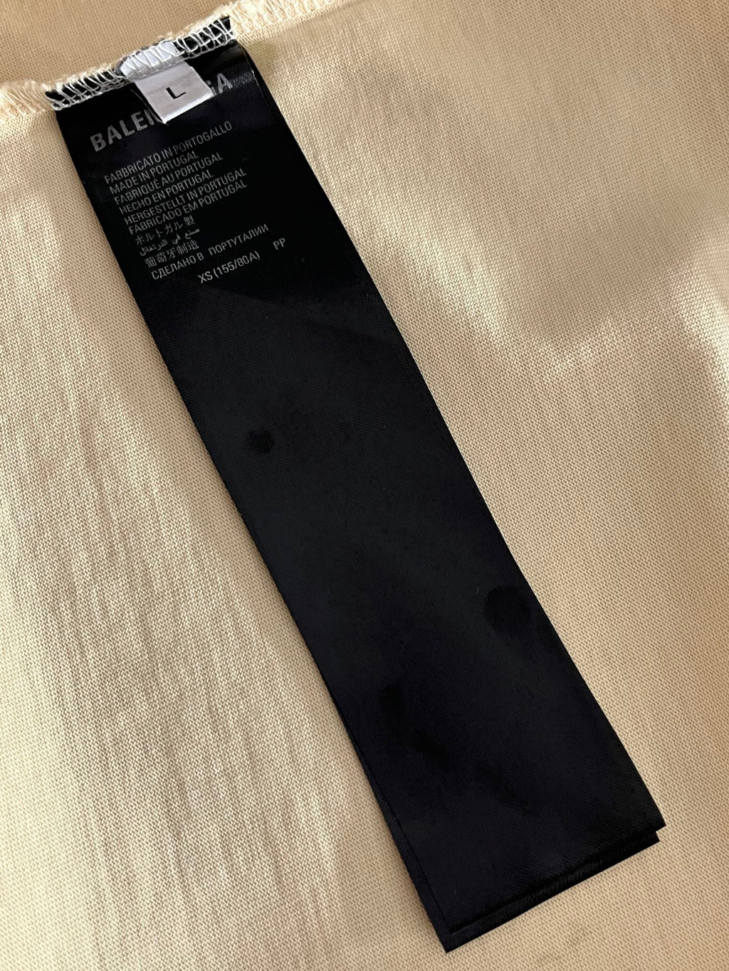 Balenciaga black clothing label tag on cream fabric