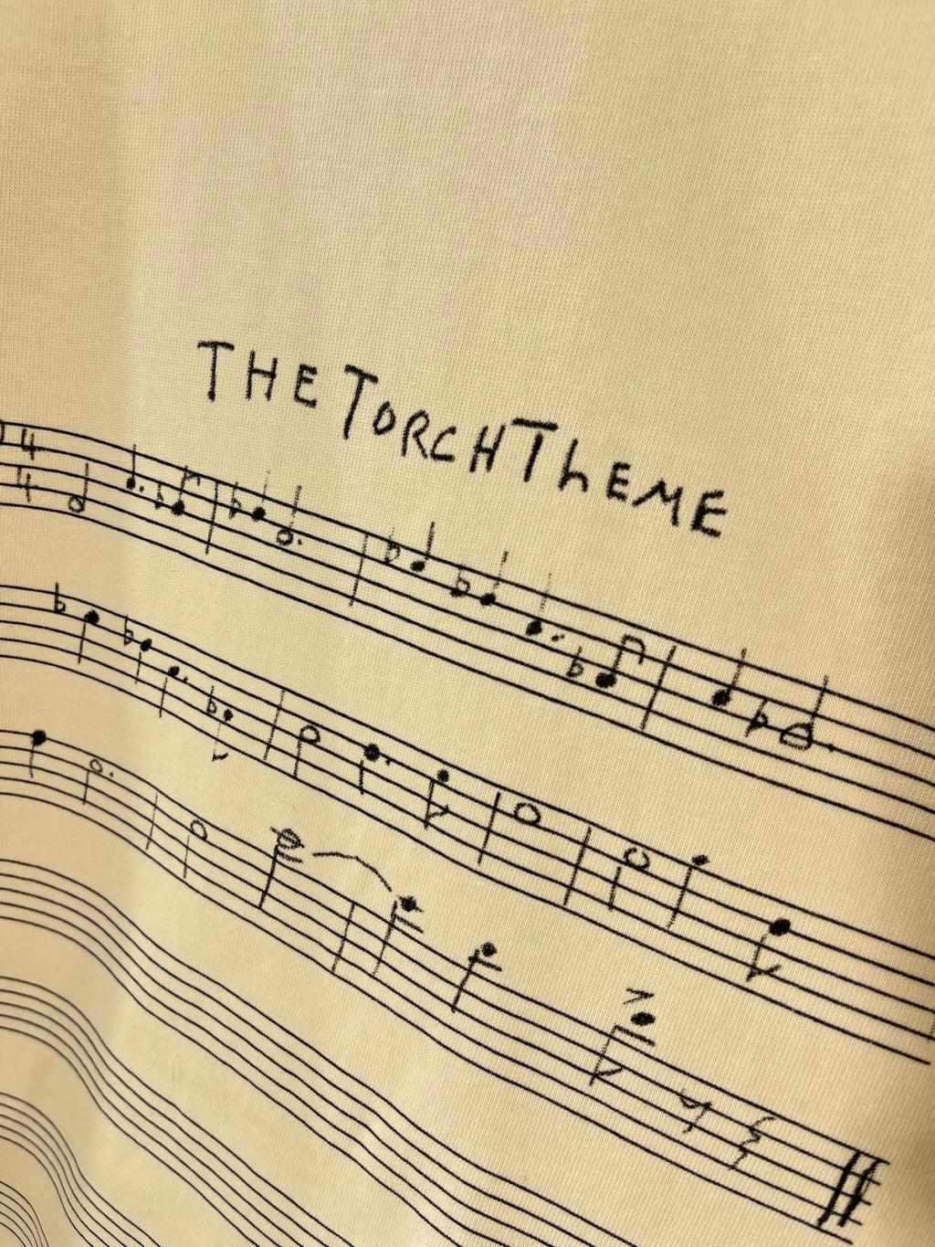 Balenciaga cream T-shirt close-up of THE TORCH THEME musical staff