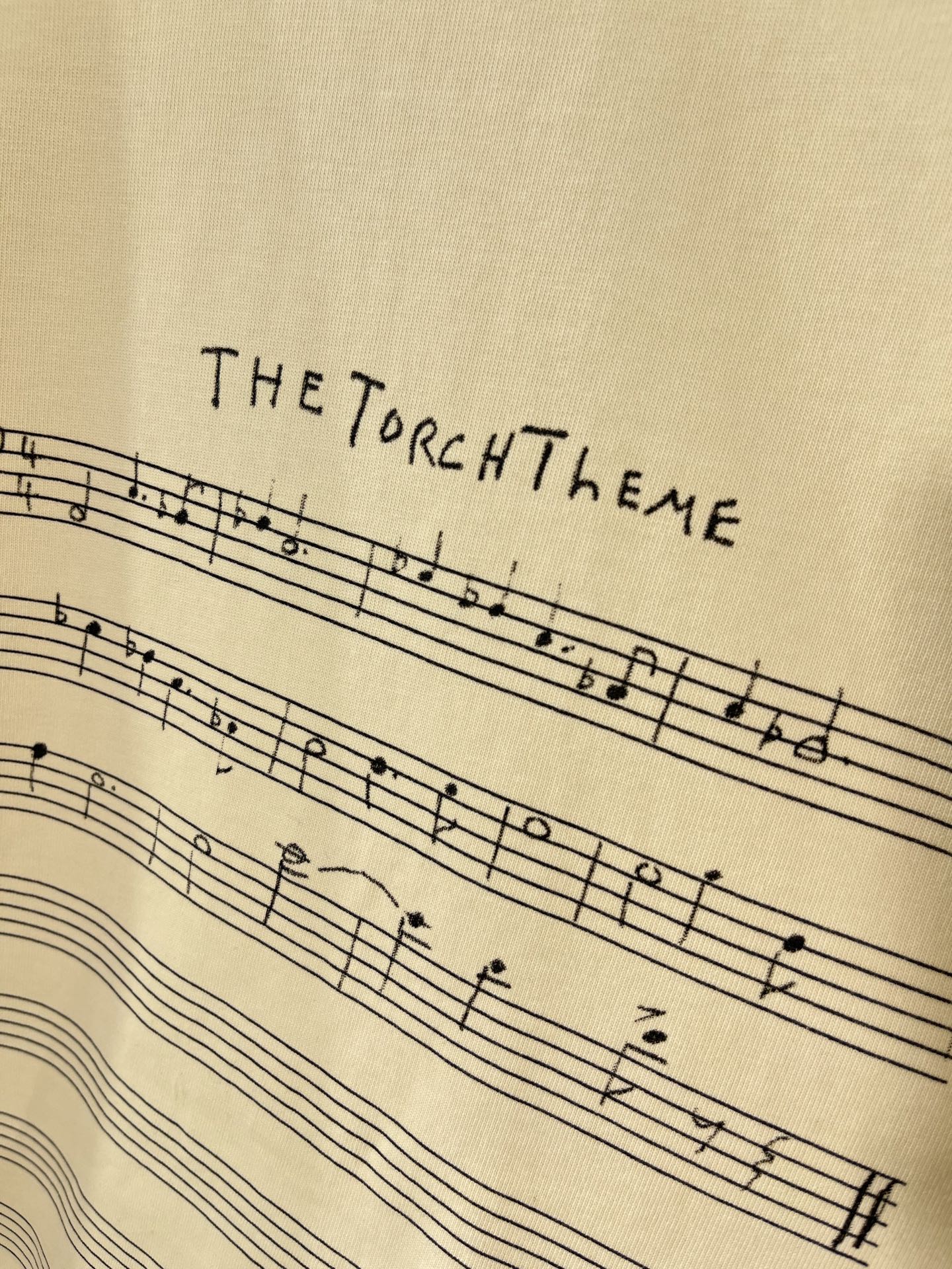 Balenciaga cream T-shirt close-up of THE TORCH THEME musical staff