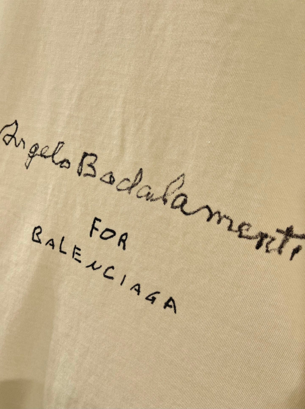 Balenciaga cream T-shirt close-up of cursive and small text graphic