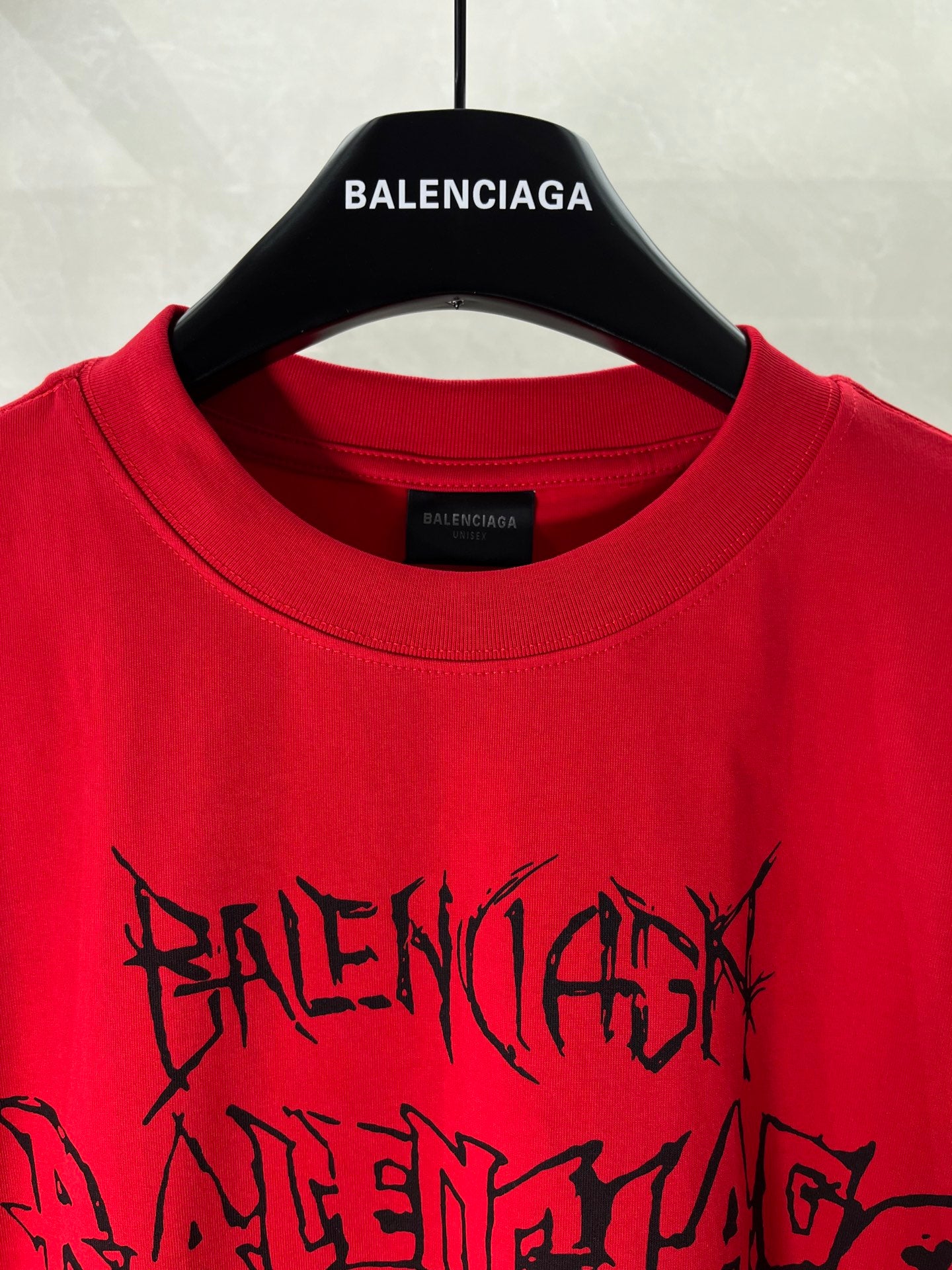 Red crew-neck T-shirt close-up with black graphic lettering and BALENCIAGA label