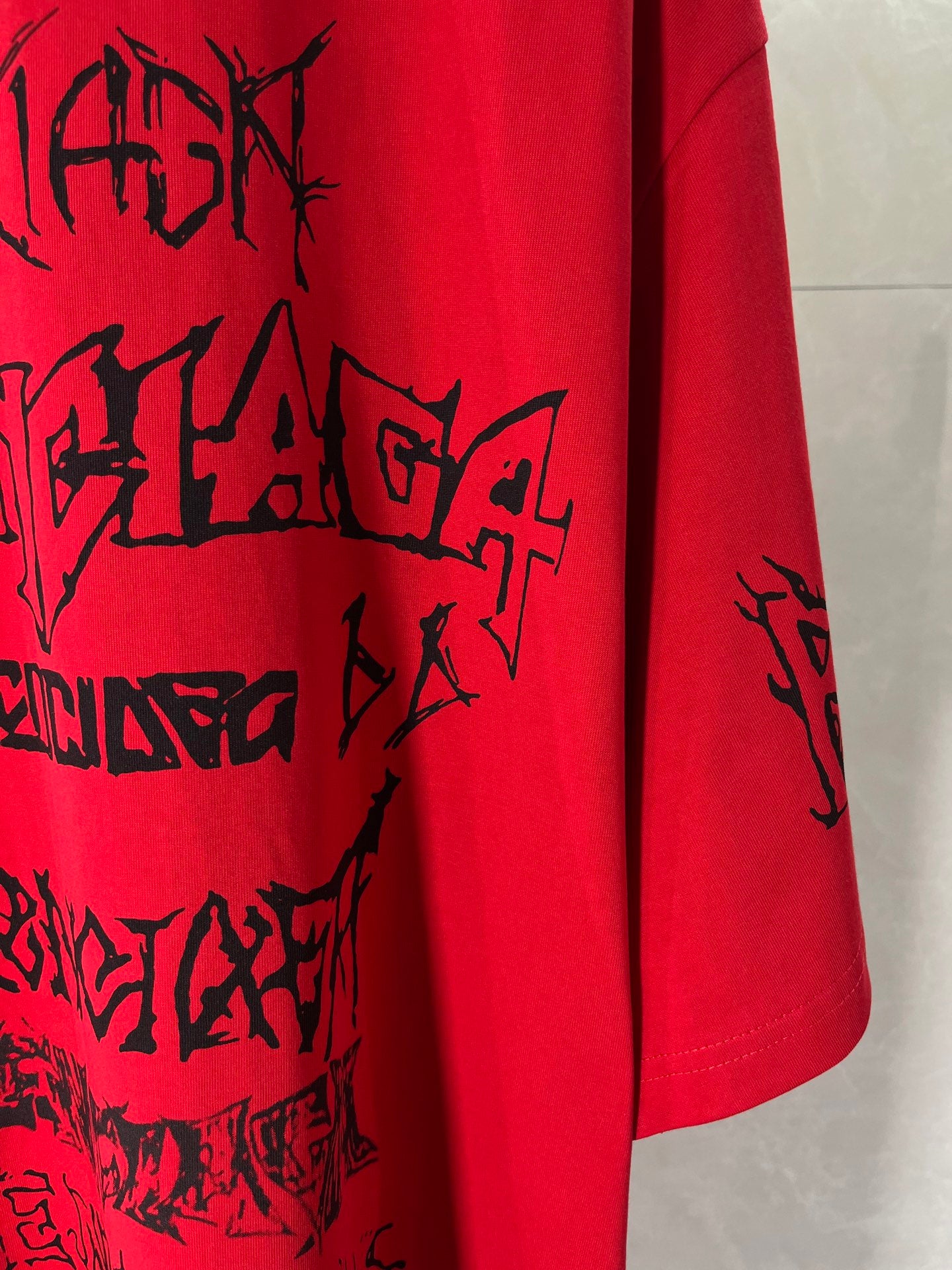 Red T-shirt side hem with black graphic print on the front
