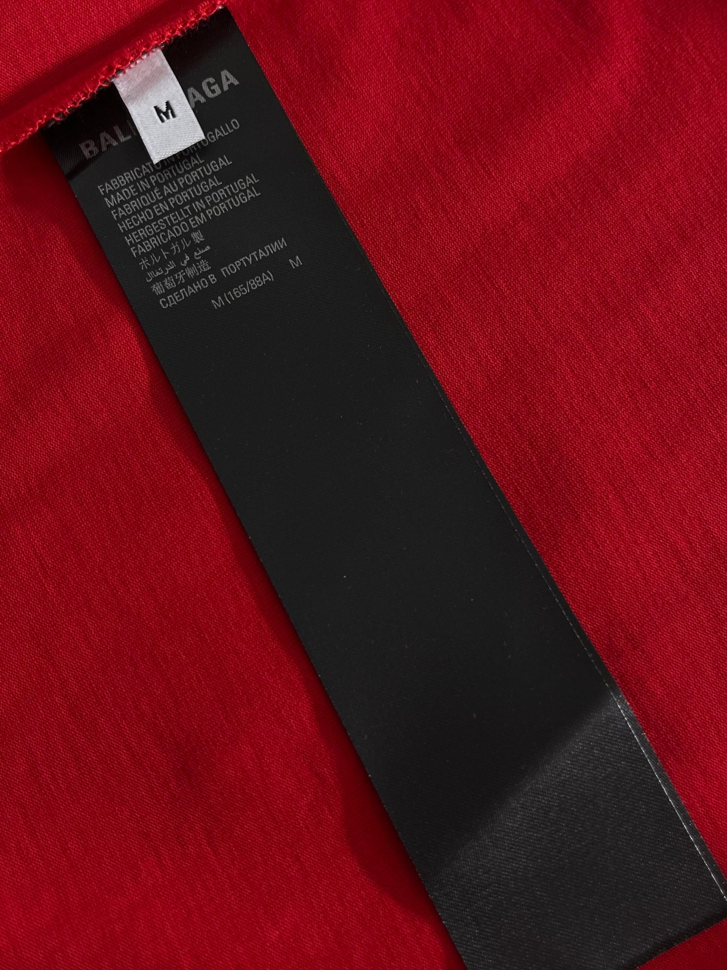 Red T-shirt fabric with black size and care label at collar seam