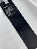 Black size label and care text on white T-shirt fabric, angled view