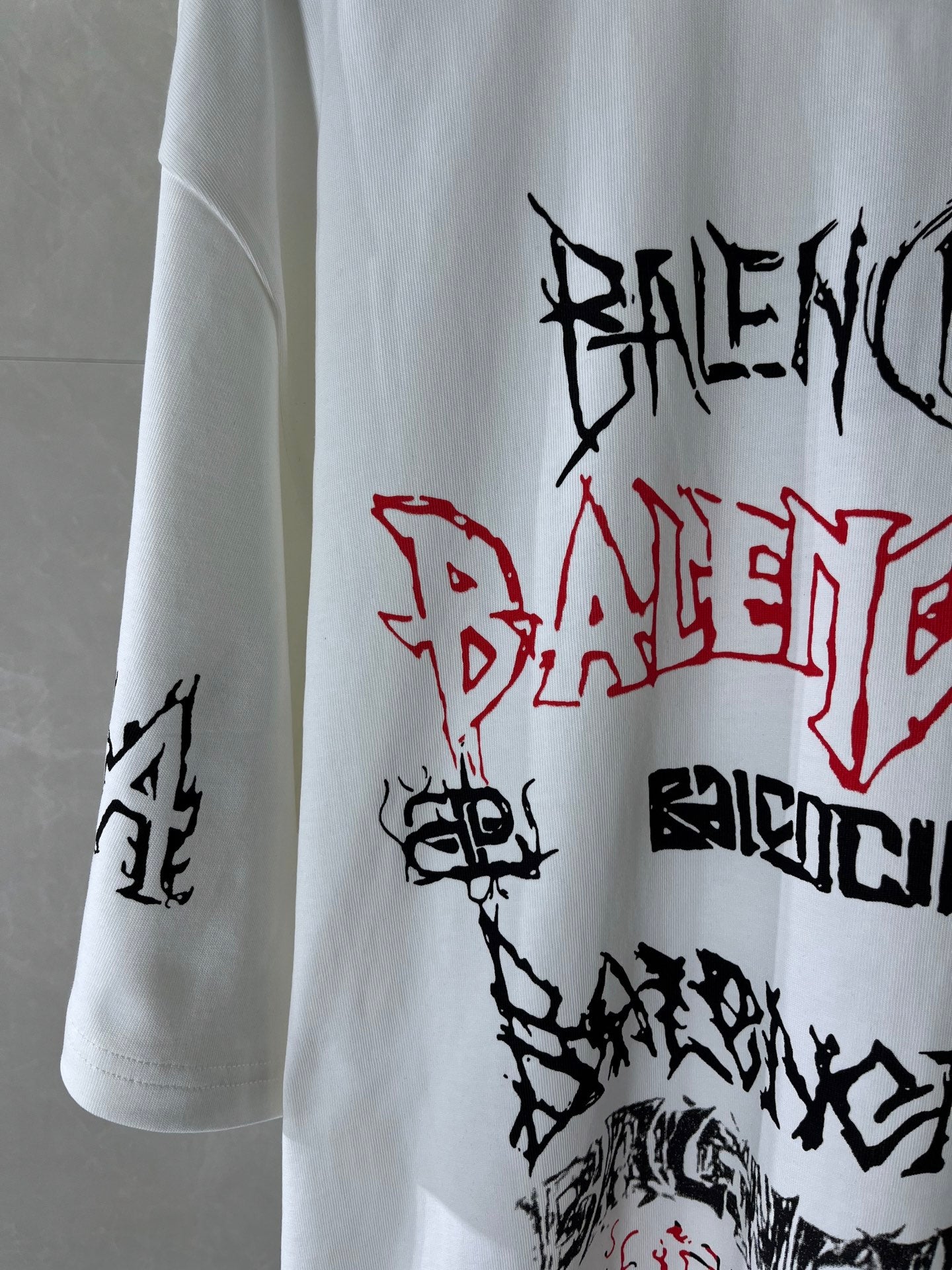 White T-shirt sleeve and front with black and red graffiti-style graphic lettering