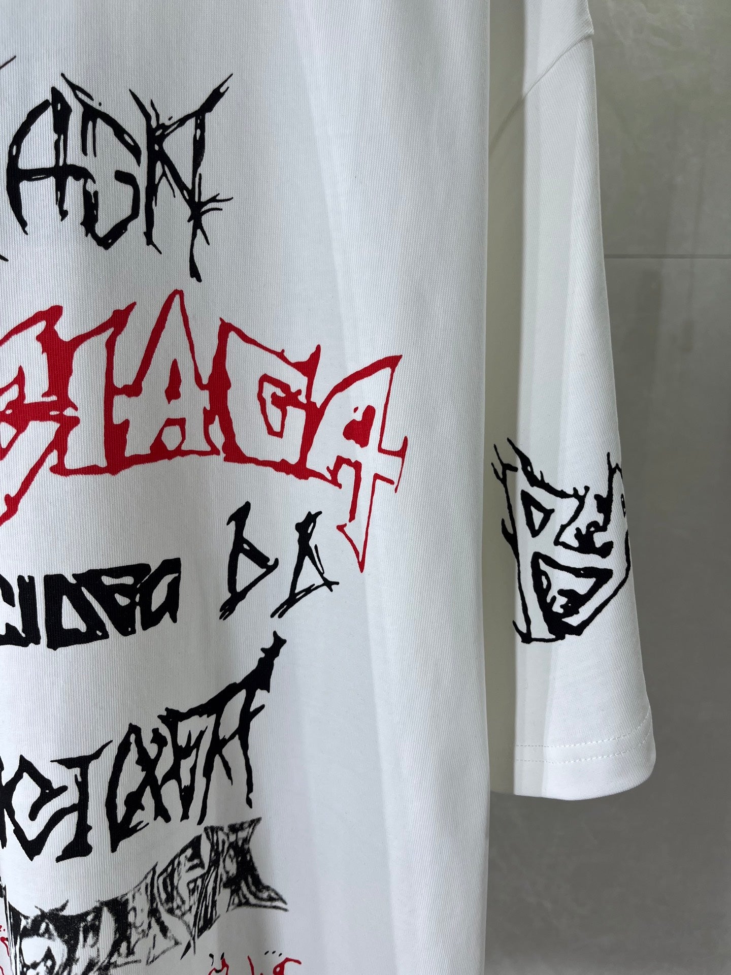 White T-shirt sleeve with black and red graffiti-style print, side view