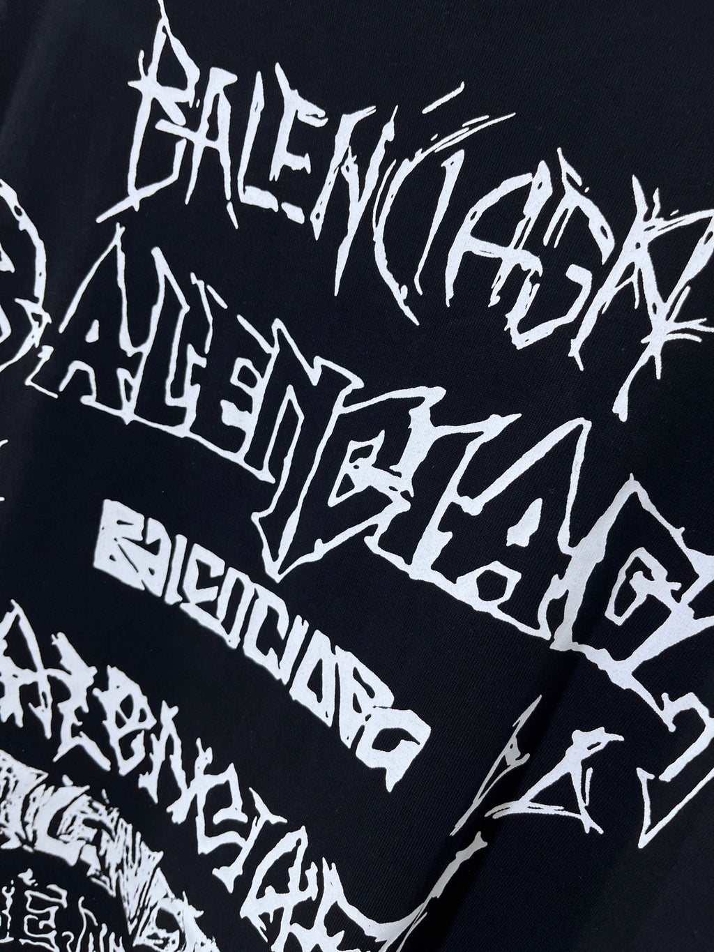 Balenciaga T-shirt graphic close-up, black fabric with dense white typographic text