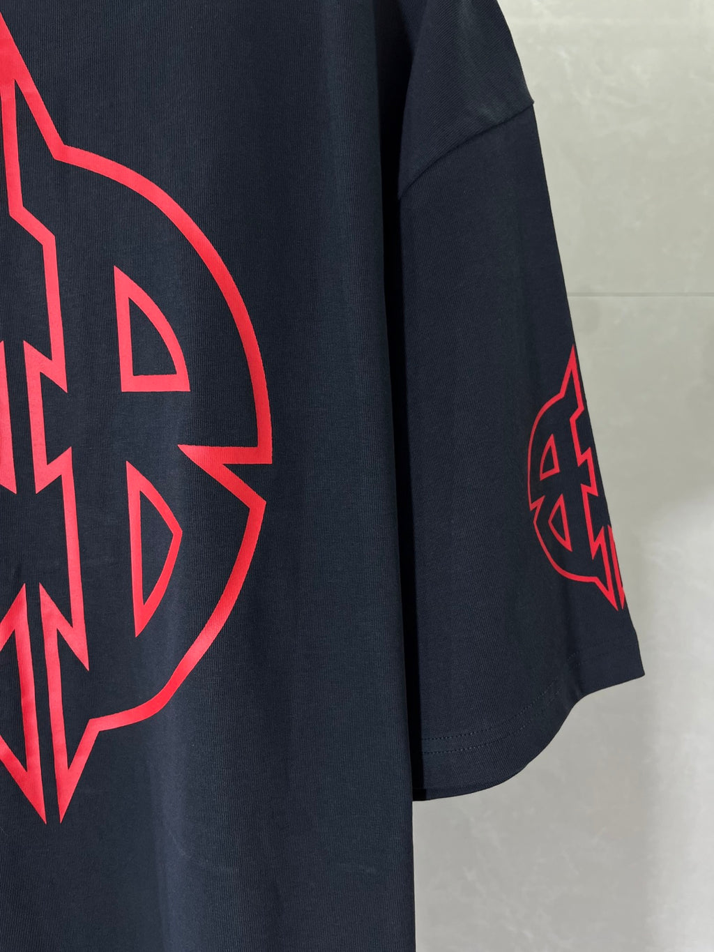 Dark navy T-shirt sleeve with small red emblem graphic.