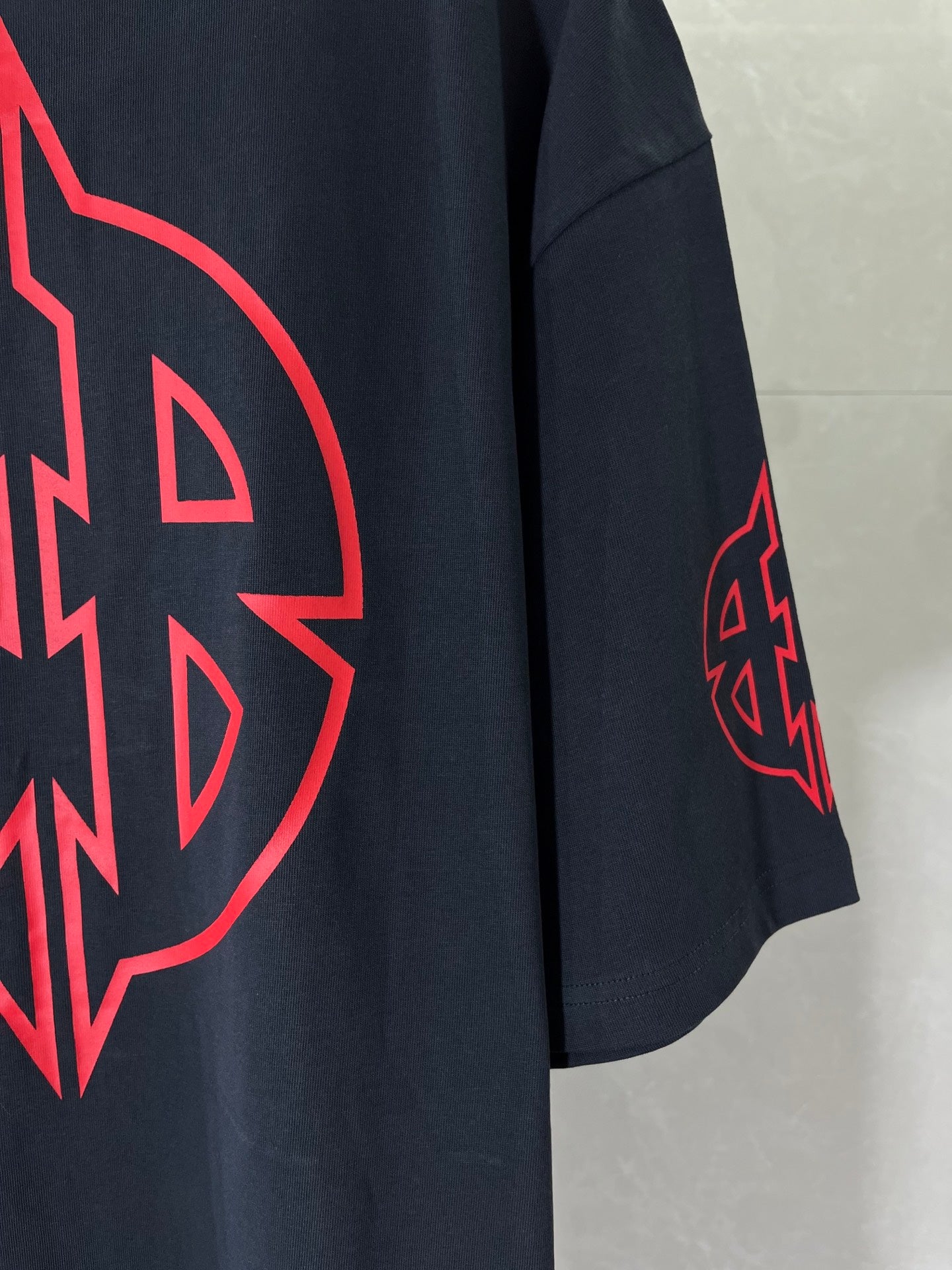 Dark navy T-shirt sleeve with small red emblem graphic.
