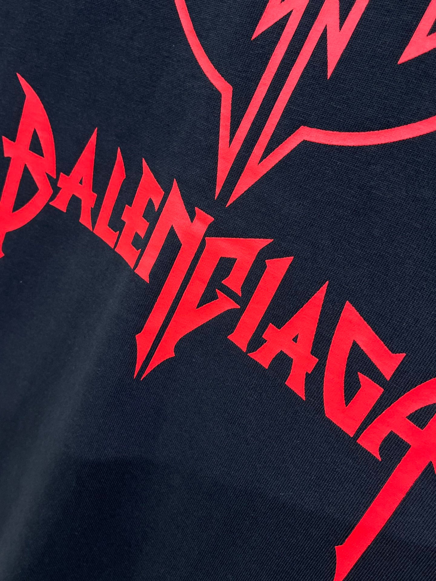 Close-up of red BALENCIAGA text graphic on dark navy T-shirt.