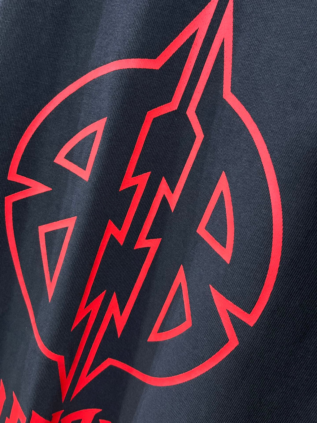 Close-up of red graphic emblem on dark navy T-shirt fabric.