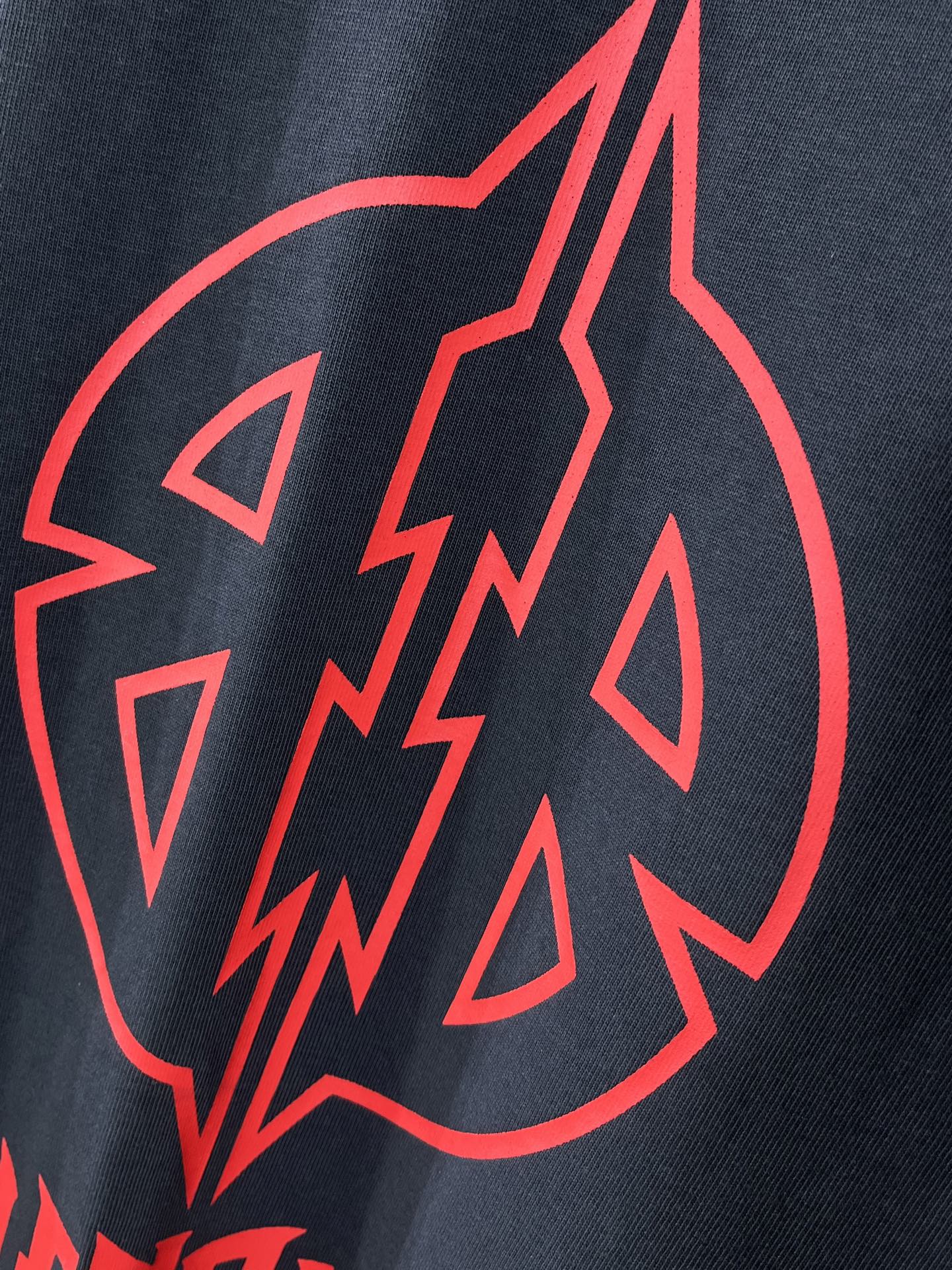 Close-up of red graphic emblem on dark navy T-shirt fabric.