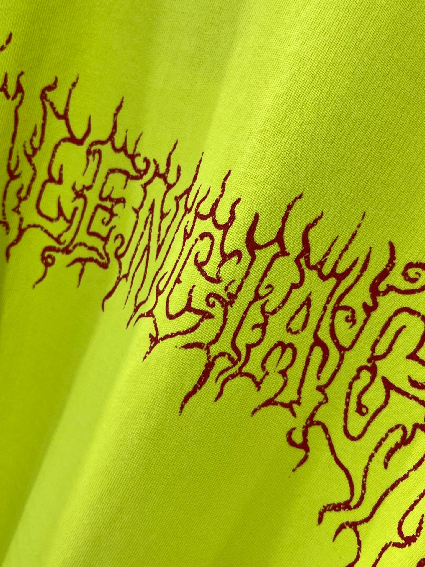 Lime green T-shirt back graphic close-up in dark red