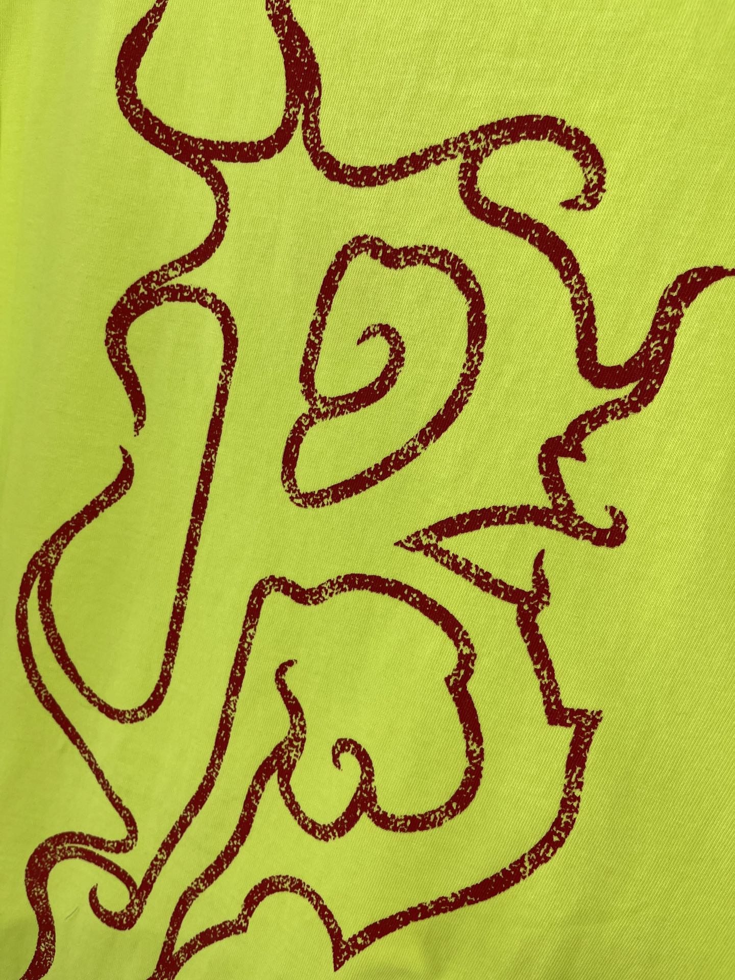 Lime green T-shirt graphic close-up with dark red line art