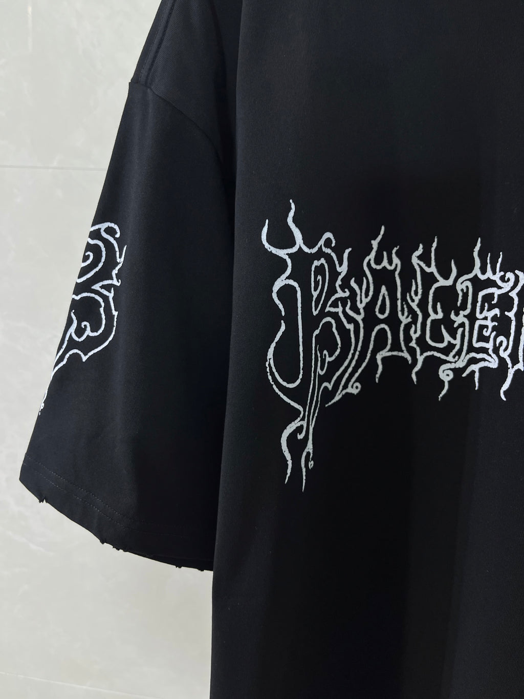 Black short-sleeve shirt with white logo graphic on sleeve