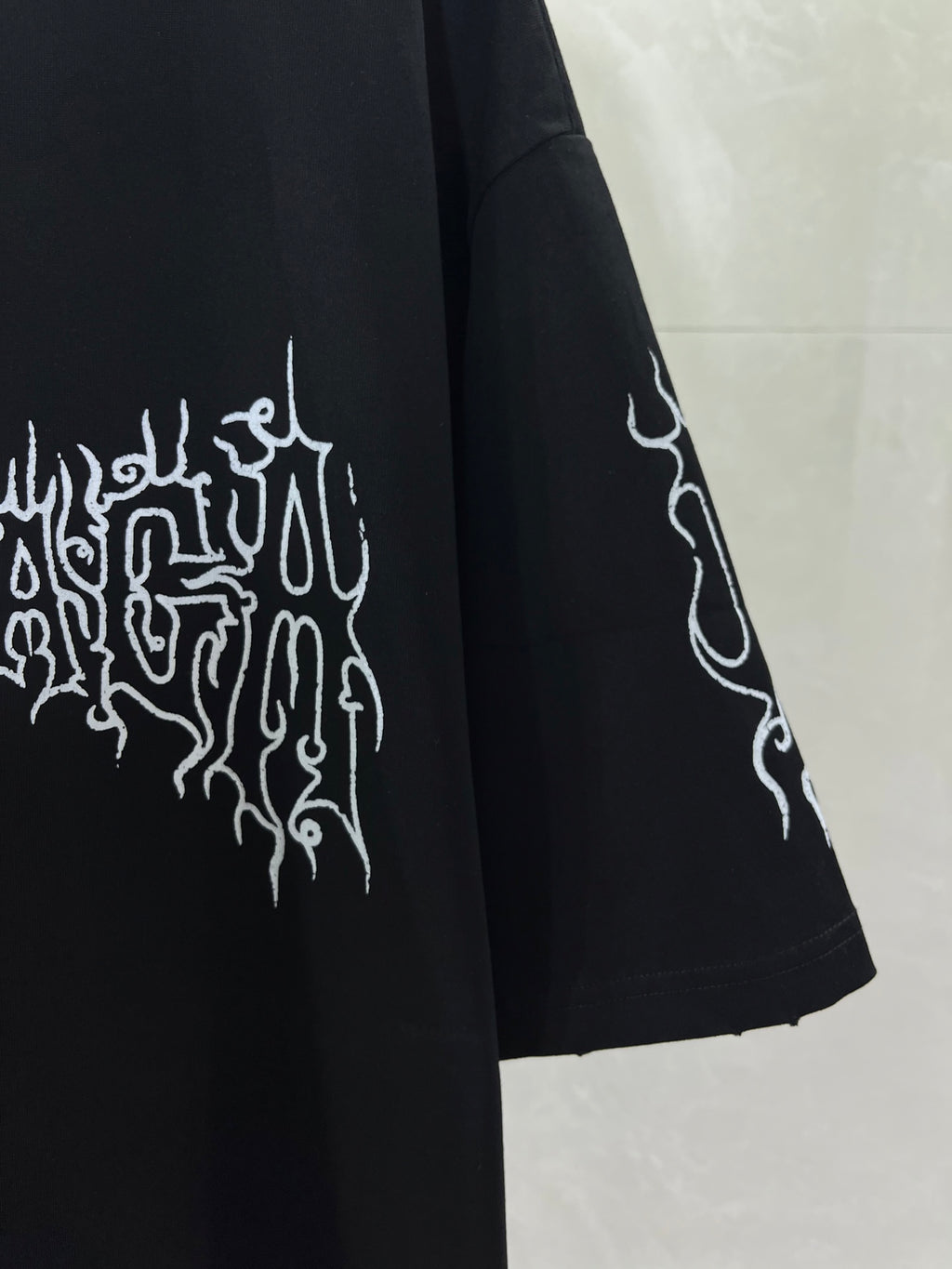 Black short-sleeve shirt with white emblem graphic and angled sleeve