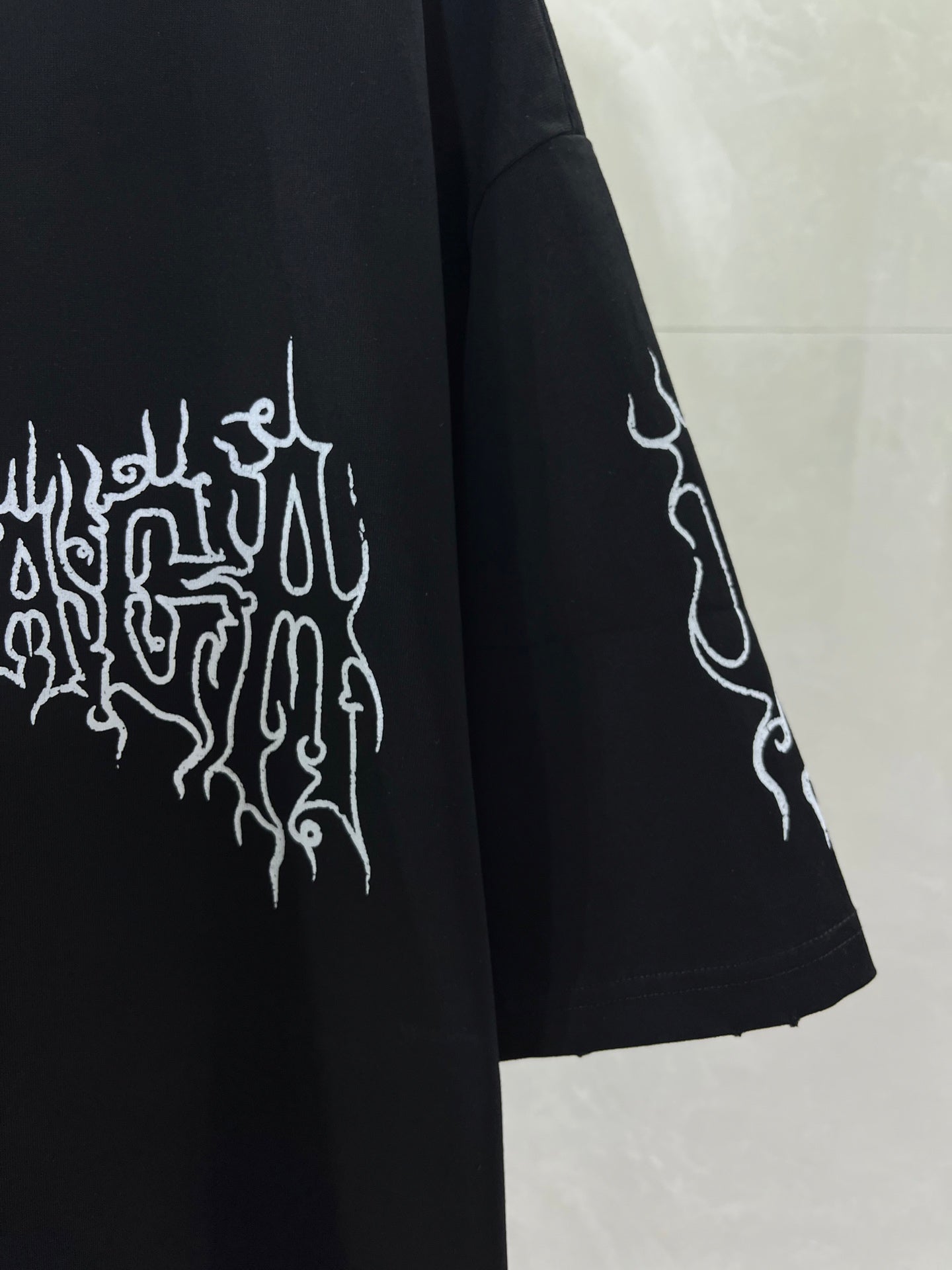 Black short-sleeve shirt with white emblem graphic and angled sleeve