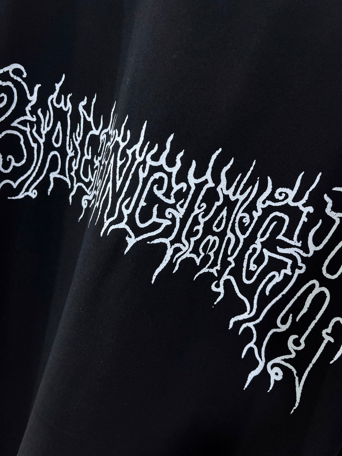 Black shirt with white ornate text-style graphic across chest
