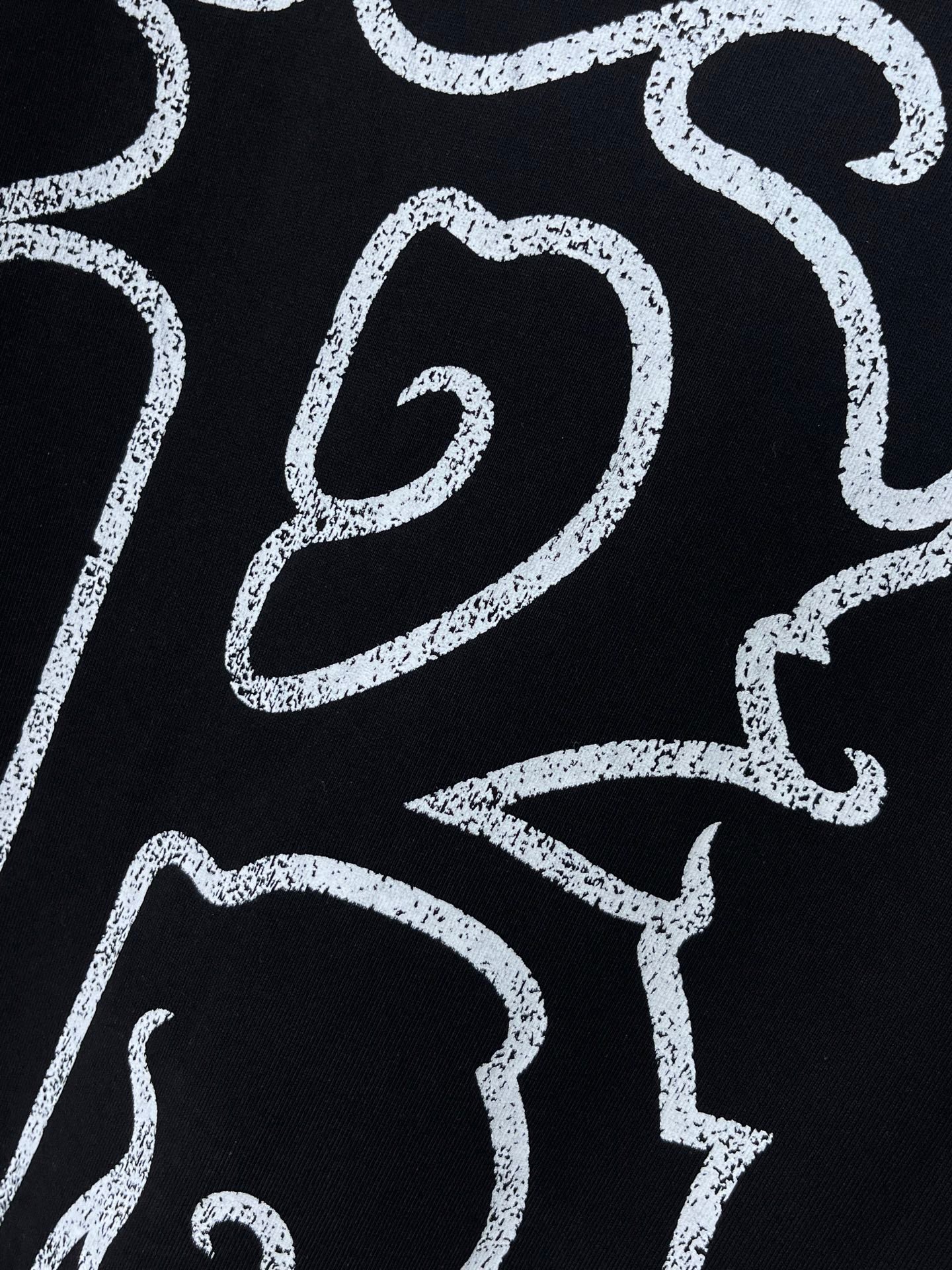 Black shirt with partial white logo text graphic detail
