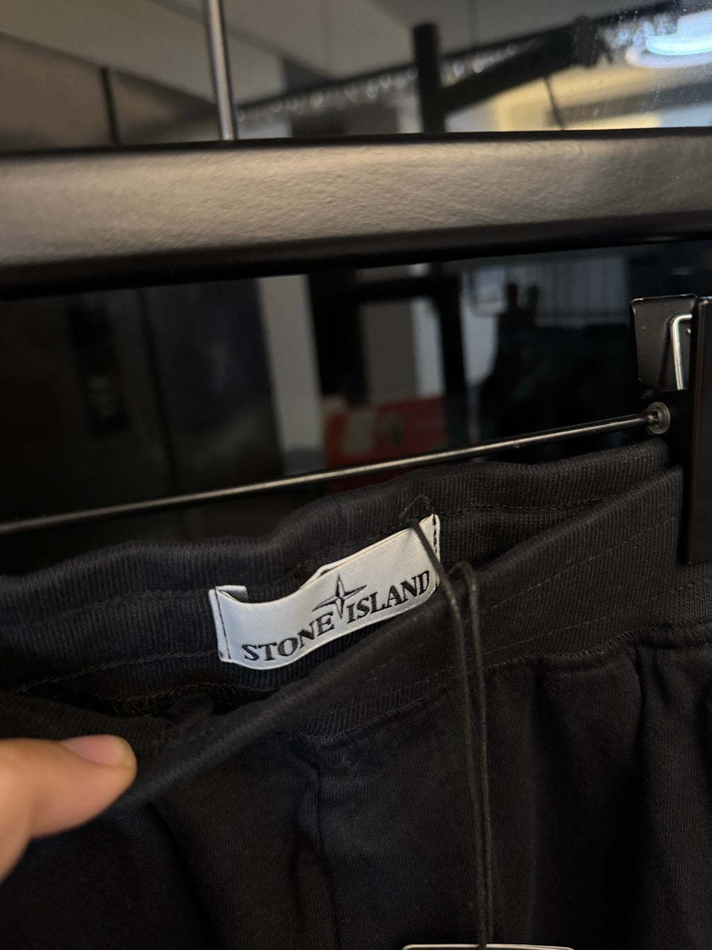 Stone Island waistband label on dark gray trousers with elastic waist and button closure