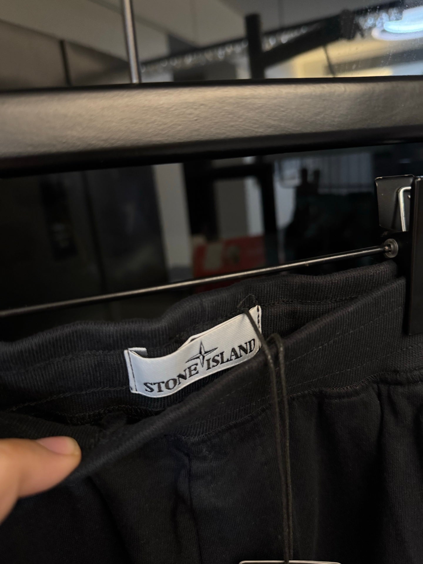 Stone Island waistband label on dark gray trousers with elastic waist and button closure