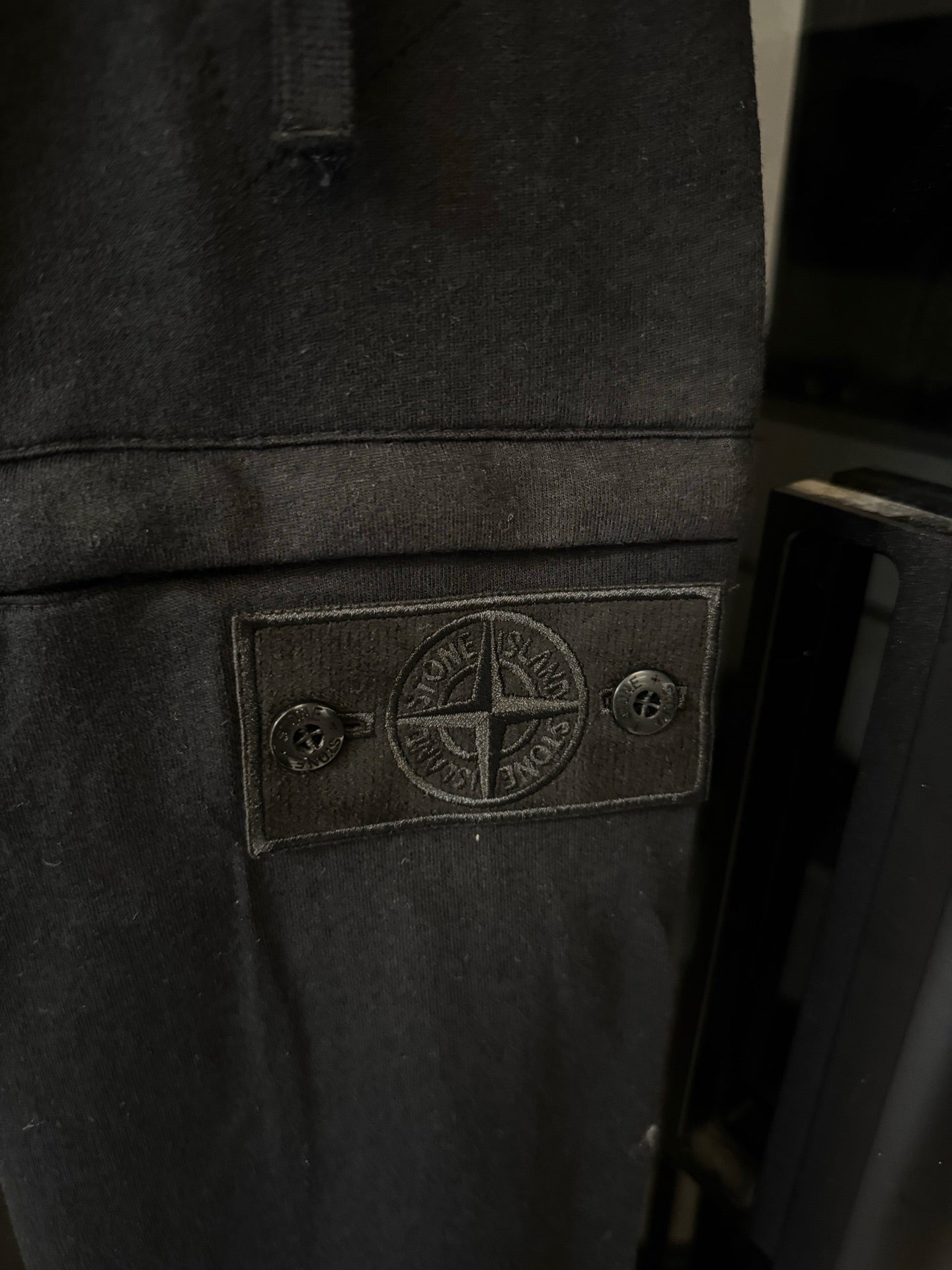 Stone Island logo patch on dark gray cargo trousers, stitched patch detail on pocket area