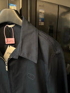 Dark navy jacket with raised collar seam detail and small chest emblem logo