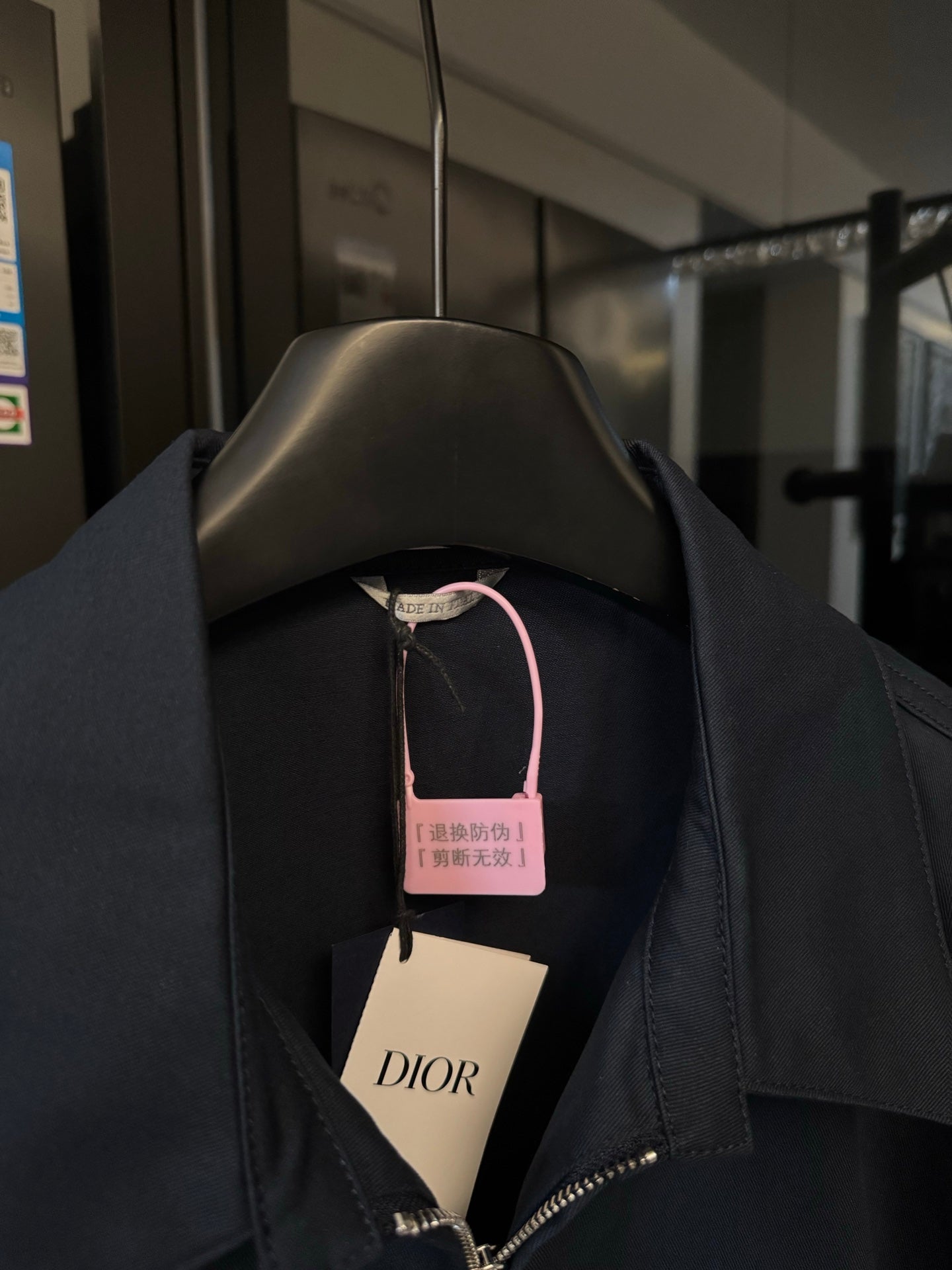 Dark navy jacket with stand collar and front zip, hang tags visible