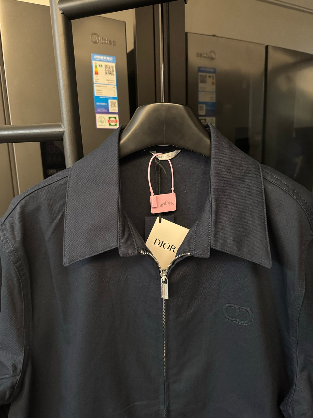 Dark navy long-sleeve zip jacket on hanger with pointed collar and Dior logo
