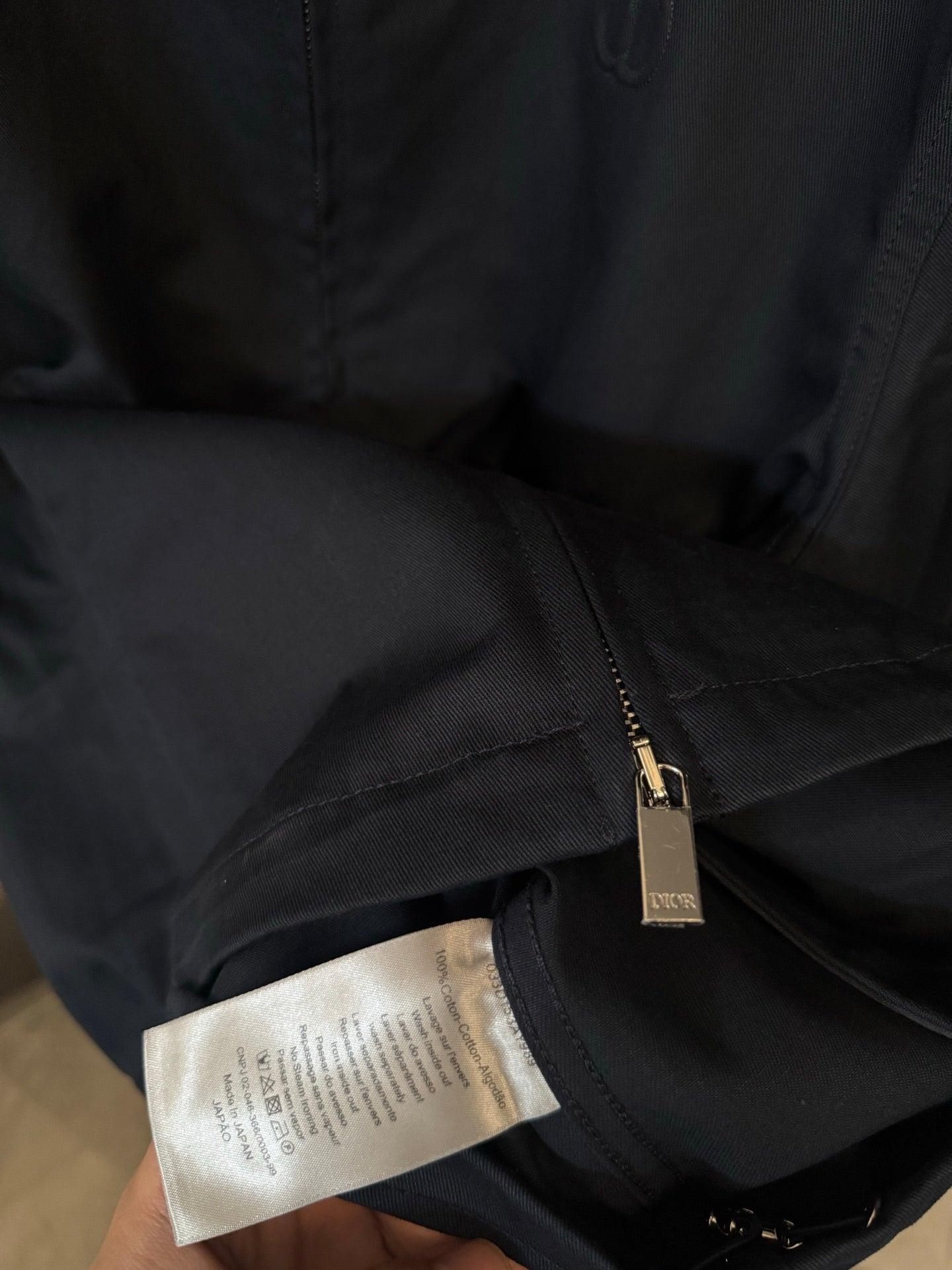 Dark navy jacket sleeve and pocket area with front zip, fabric close-up