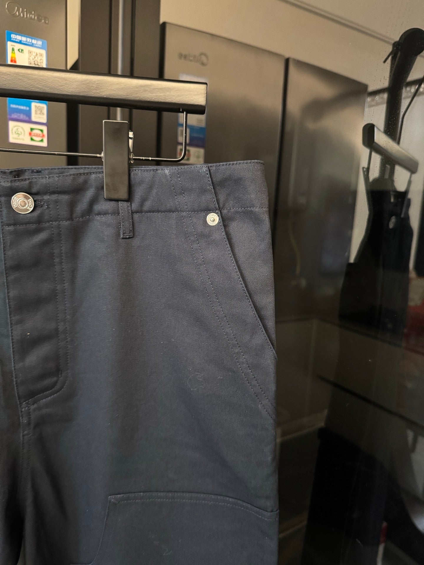 Dark blue trousers with belt loops and coin-style button at waistband