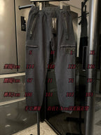 Stone Island cargo trousers on display, dark gray with drawstring and size markers on glass