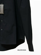 Balenciaga black long-sleeve shirt with front buttons and curved hem; close-up
