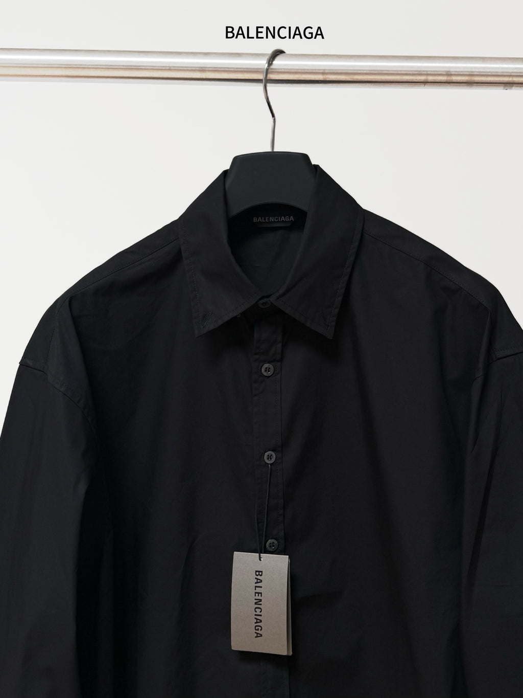 Black long-sleeve button-up shirt with pointed collar and front button placket; tag.