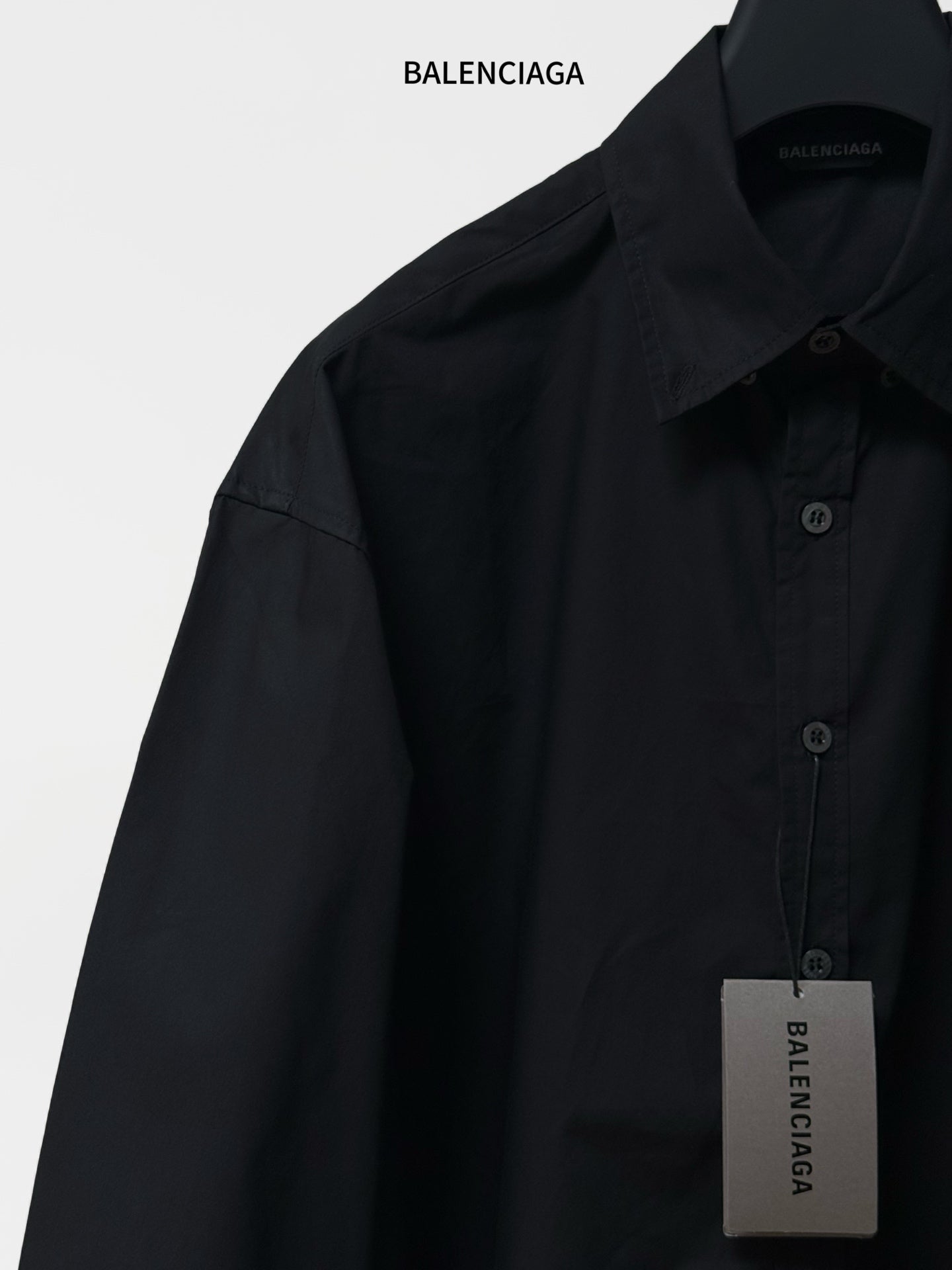 Black long-sleeve button-up shirt with pointed collar; front buttons and size tag.