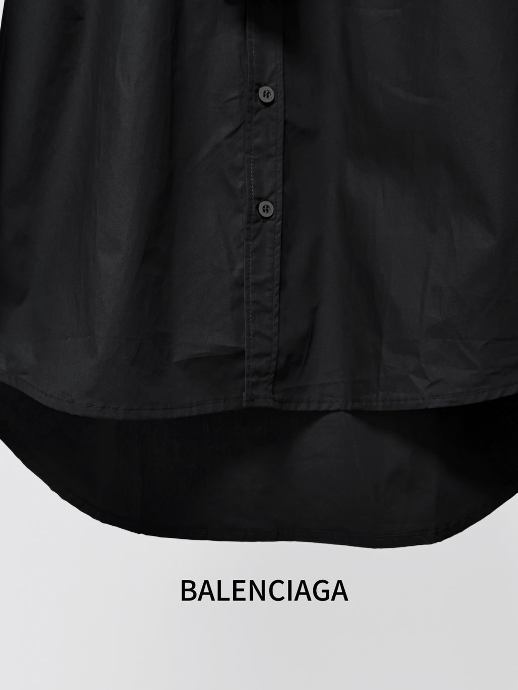 Balenciaga black shirt hem with button placket and curved lower edge; close-up