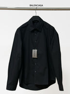 Black long-sleeve button-up shirt with pointed collar and front button placket.