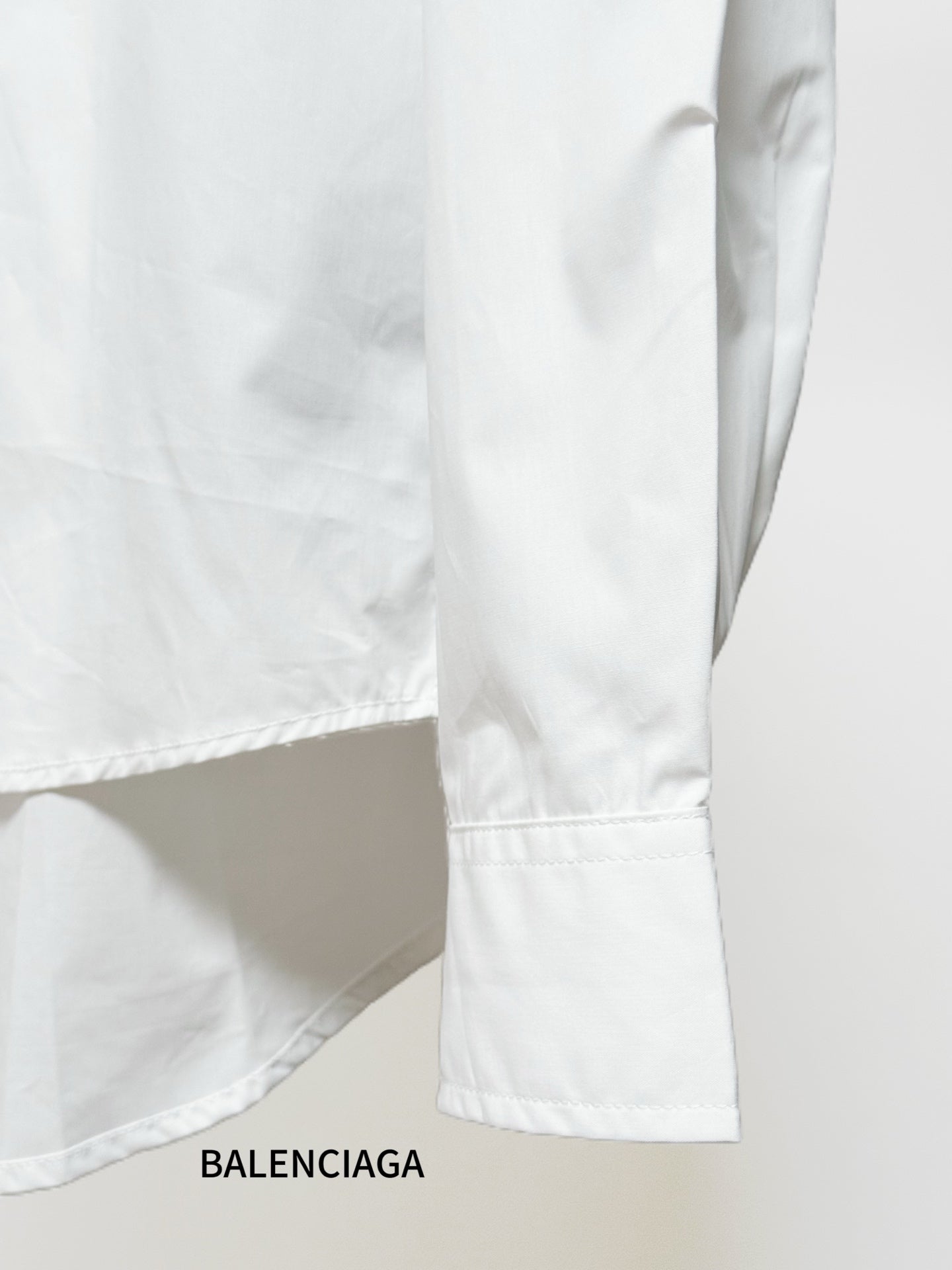 White shirt sleeve and side hem with stitched seam and cuff