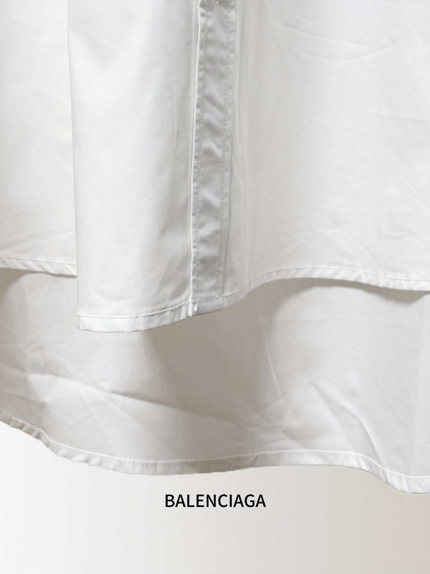 White shirt hem and side seam stitching, draped fabric fold