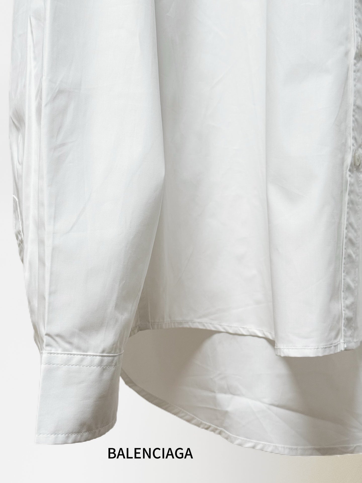 White shirt showing side seam, curved hem, and sleeve cuff