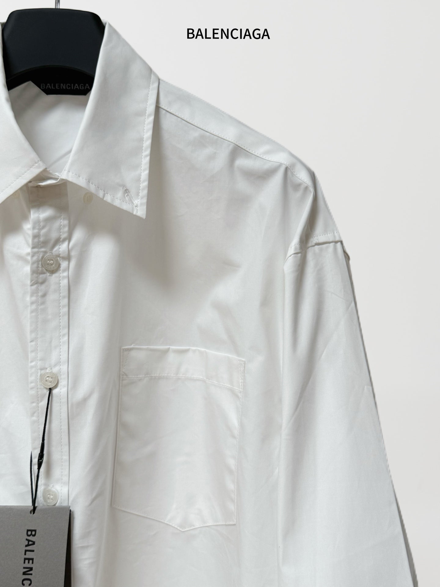 White button-up shirt chest pocket and front buttons; long sleeves; BALENCIAGA hang tag