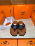 Black leather thong sandals with H logo straps and tan-brown soles.