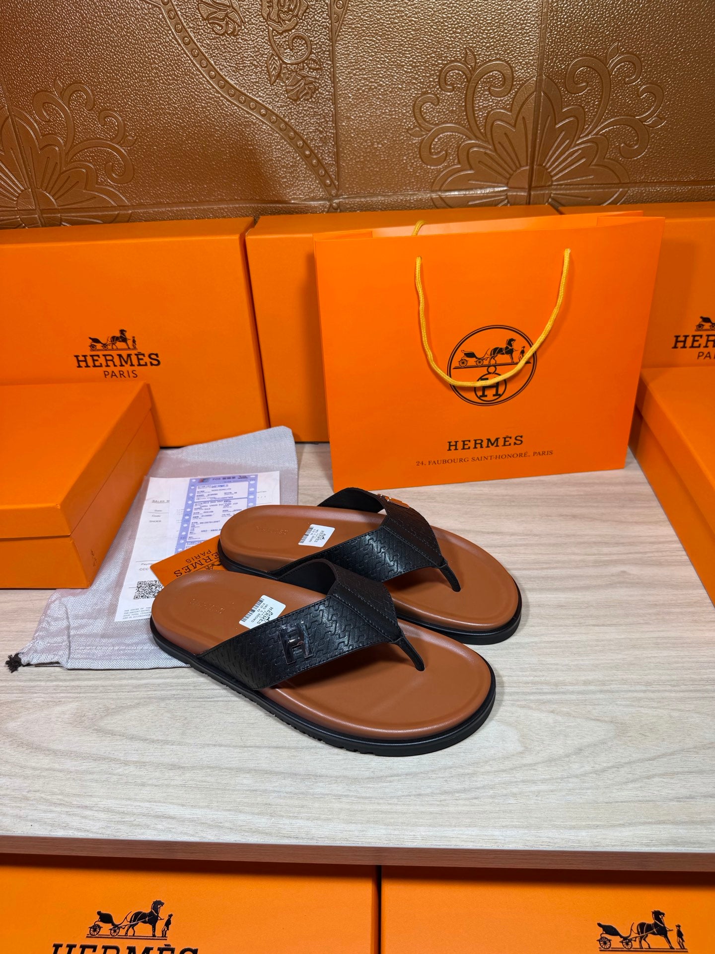 Black leather thong sandals with H logo straps and brown footbeds.