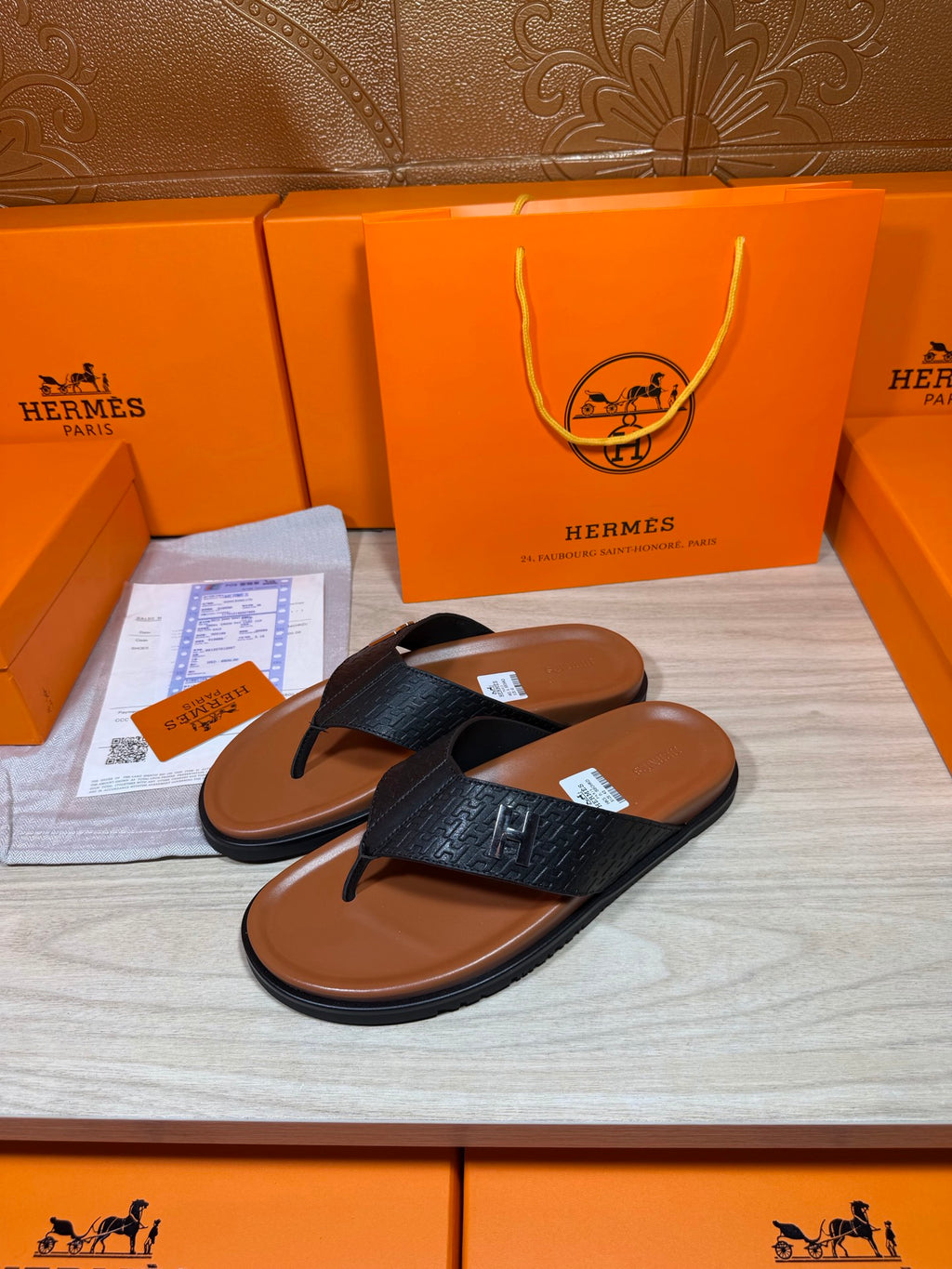 Pair of black textured leather thong sandals with H logo detail on straps.