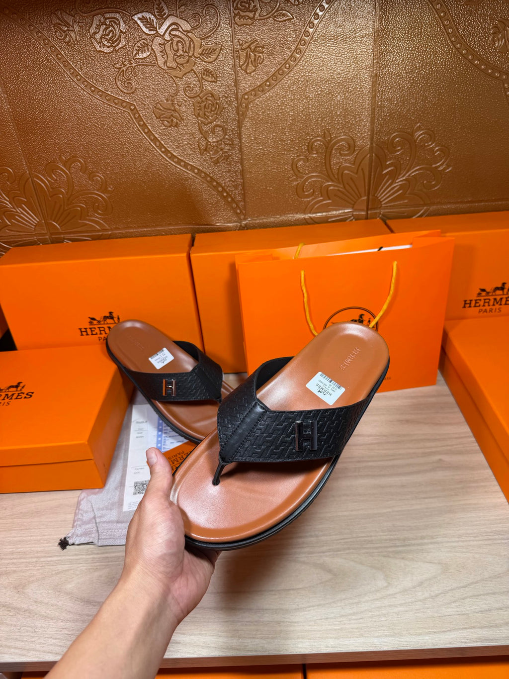 Hand-held black leather thong sandals with H logo strap over tan footbeds.