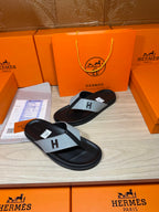 Black thong sandal with light gray cross strap featuring an H logo