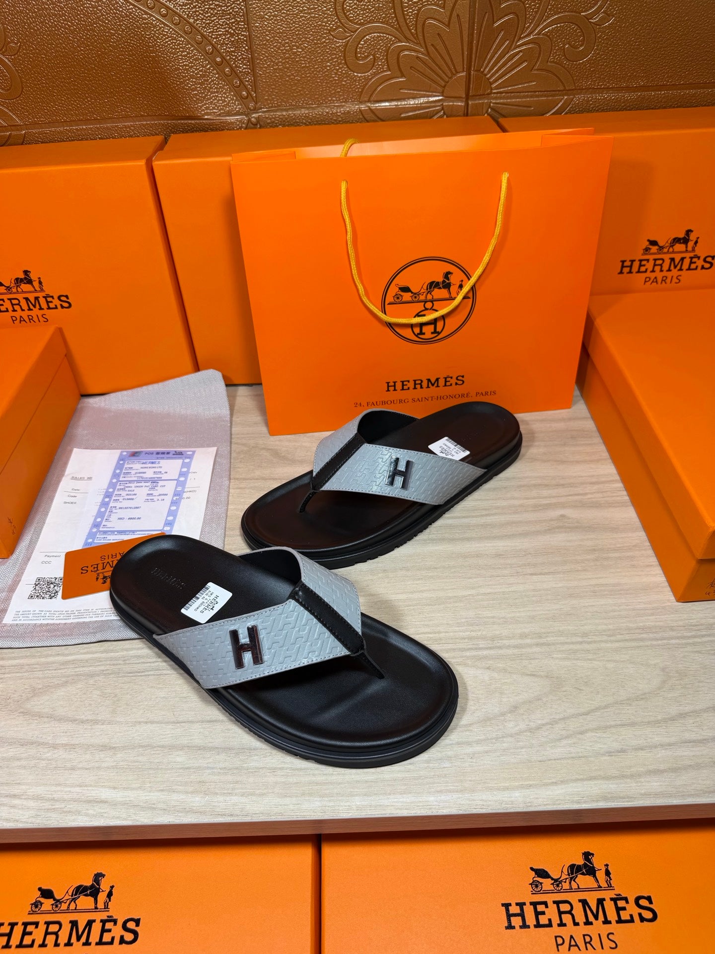 Black thong sandal with light gray cross strap featuring an H logo