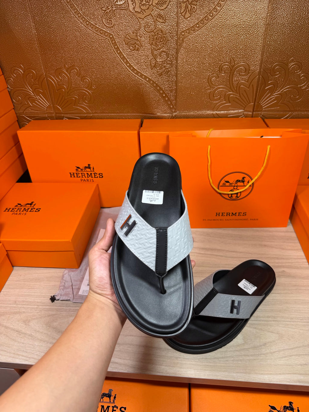 Single black thong sandal with light gray strap and H logo on footbed