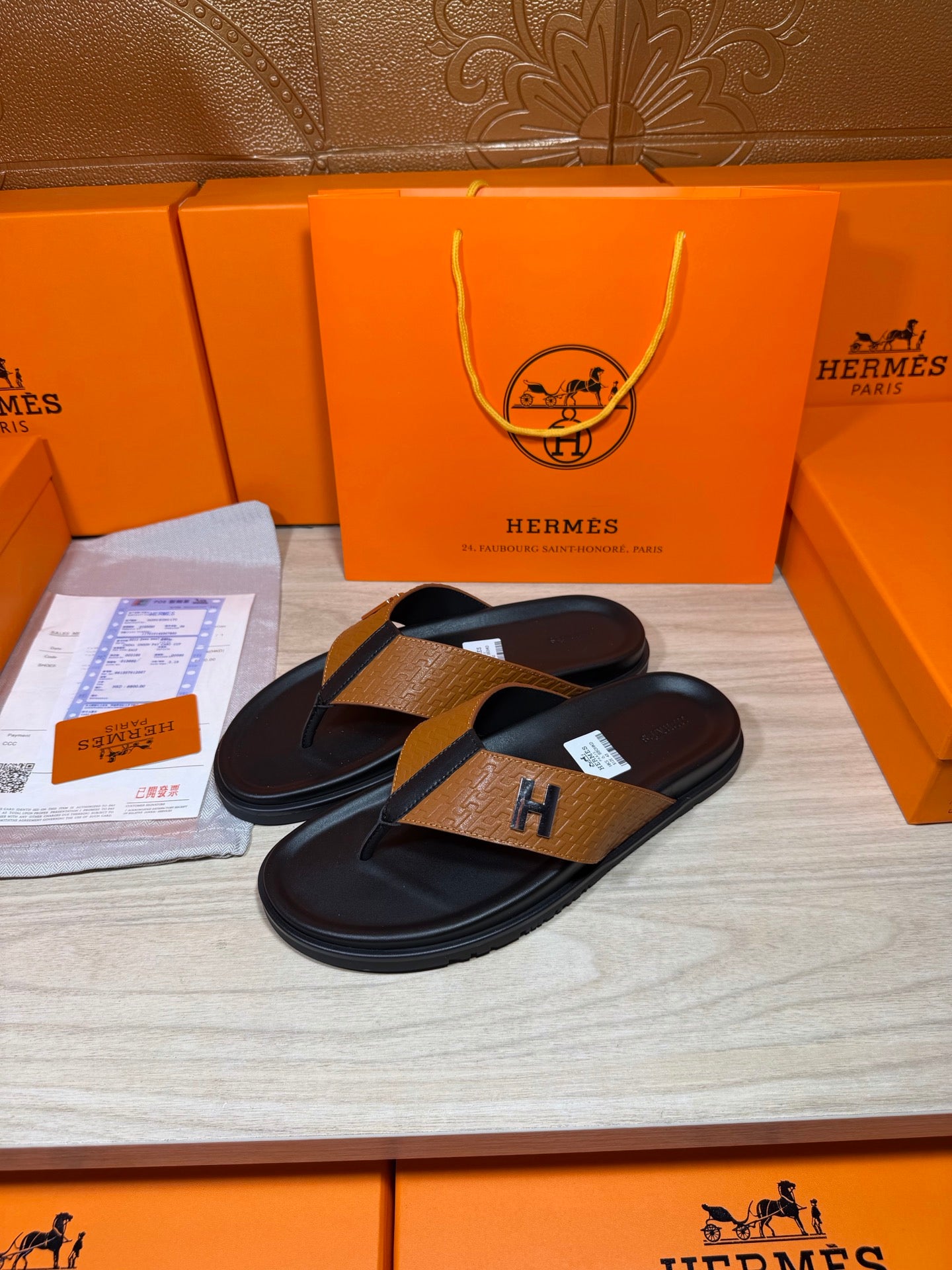 Hermes black leather thong sandals with tan strap and H logo buckle, side view