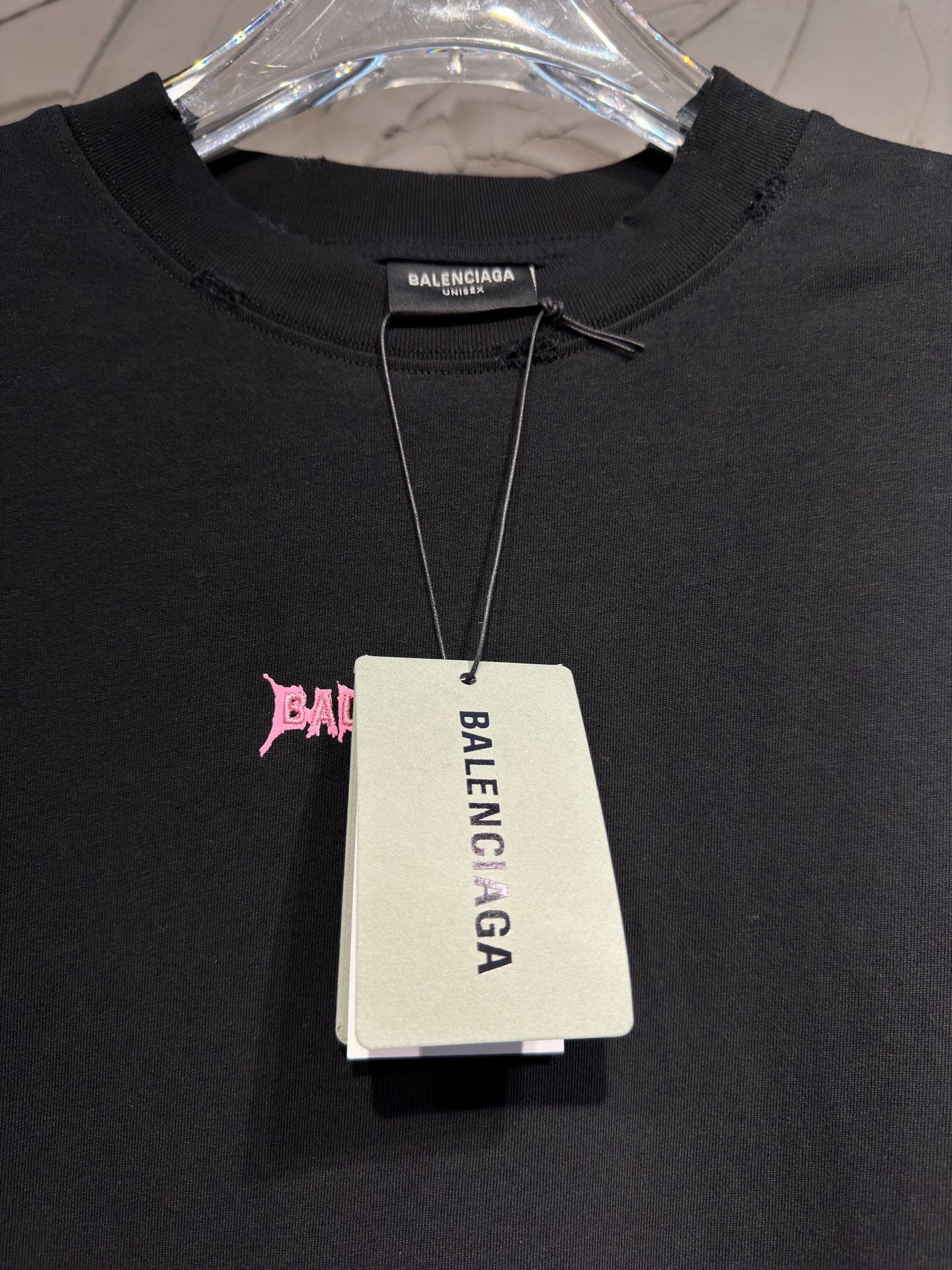 Black T-shirt with Balenciaga neck tag hanging from collar